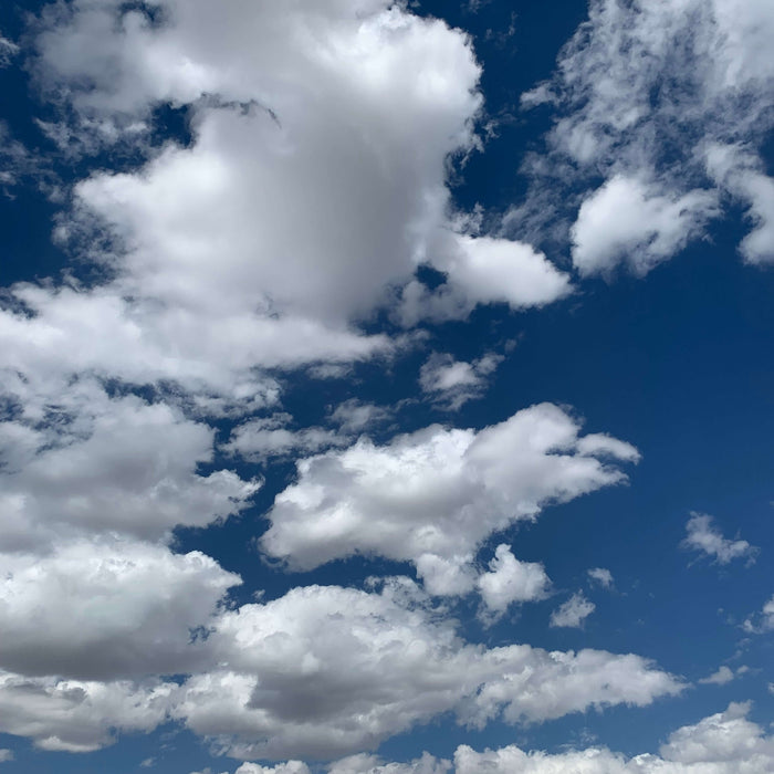 Fluffy white clouds against a deep blue sky conveying a sense of peace and spiritual wellness.