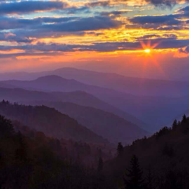 Stunning sunrise over the Great Smoky Mountains, showcasing vibrant colors and misty layers of distant peaks.