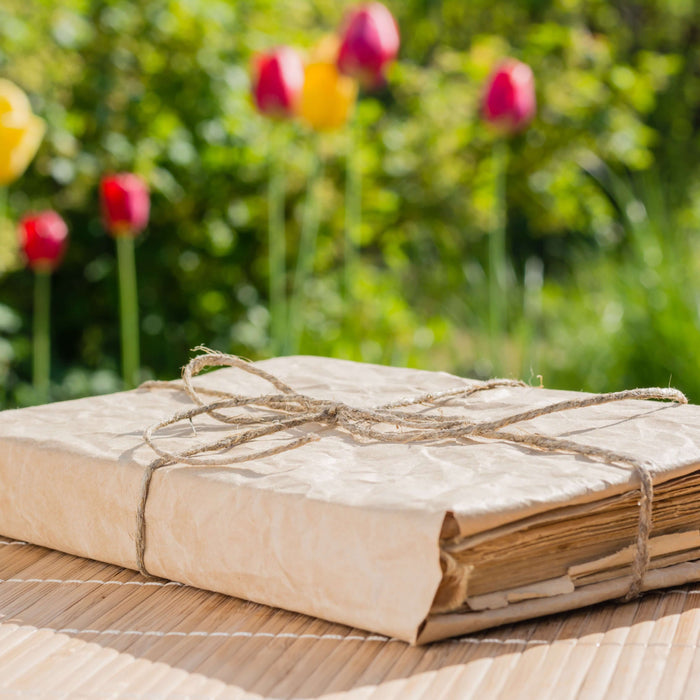 Vintage book wrapped in twine on bamboo mat with colorful tulips in background